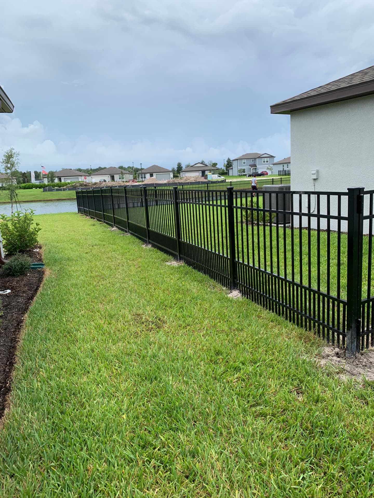 4 ft black aluminum fence with integrated puppy guard along a lakefront backyard